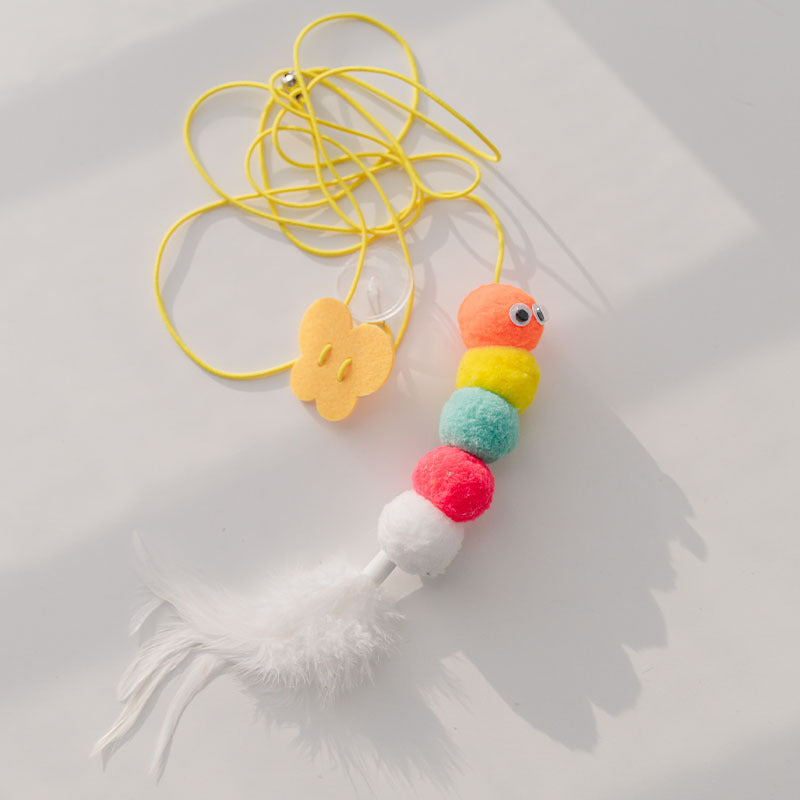 Colorful caterpillar plush toy with feather tail and yellow elastic rope on white surface