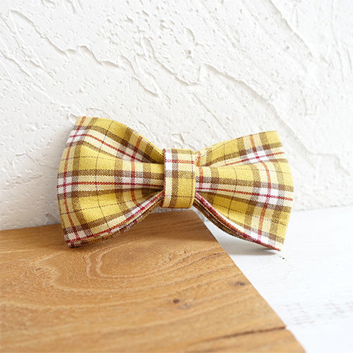 Close-up of yellow plaid bowknot accessory on a wooden surface
