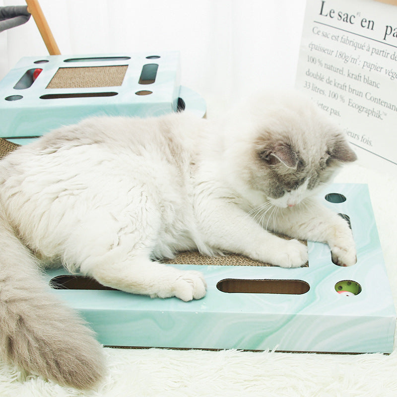 Cat playing on a rectangular light blue corrugated paper scratcher with a ball inside