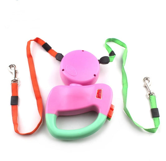 Pink and green dual retractable dog leash with orange and green nylon straps laid out flat, showing leash clips