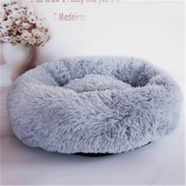 Light gray fluffy round pet bed with anti-slip base in studio lighting