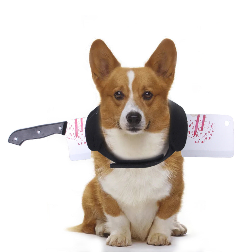 Corgi dog sitting indoors wearing black Halloween costume harness with bloody cleaver prop attached behind neck