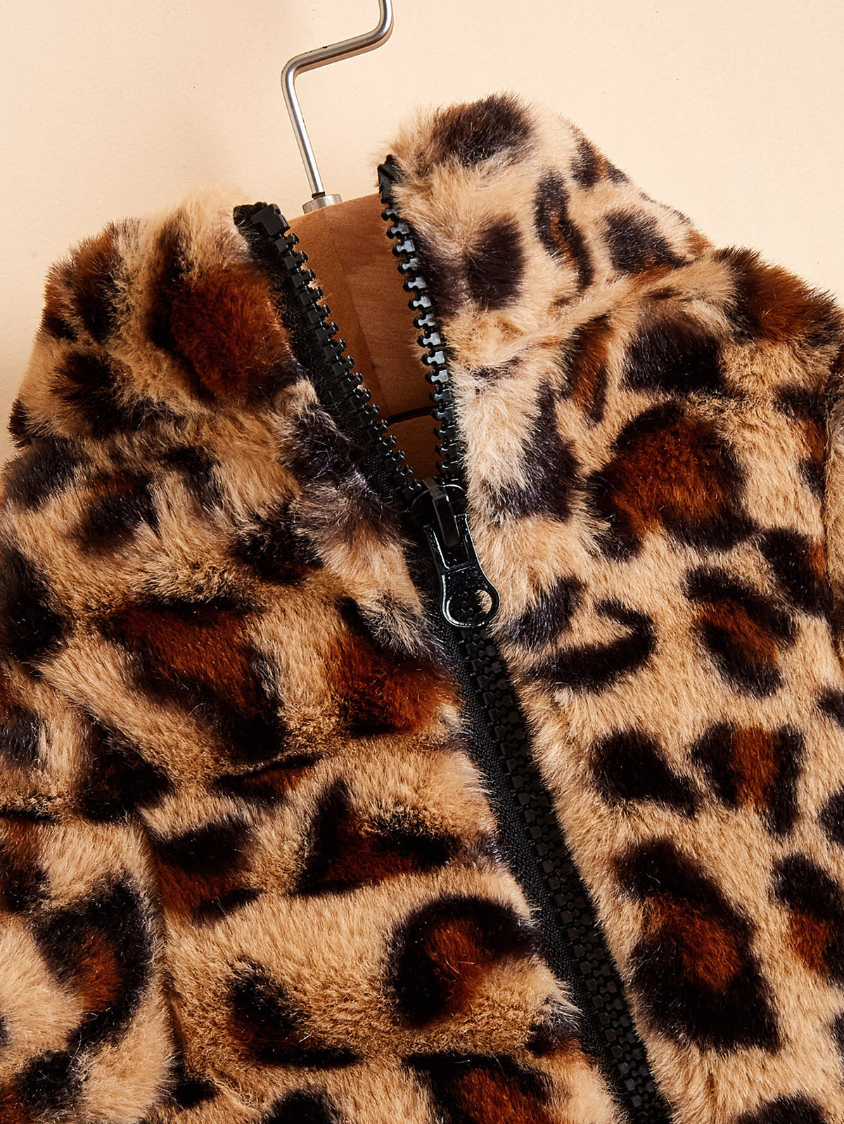 Close-up view of the zipper and soft fuzzy acrylic leopard print fabric on the dog jacket