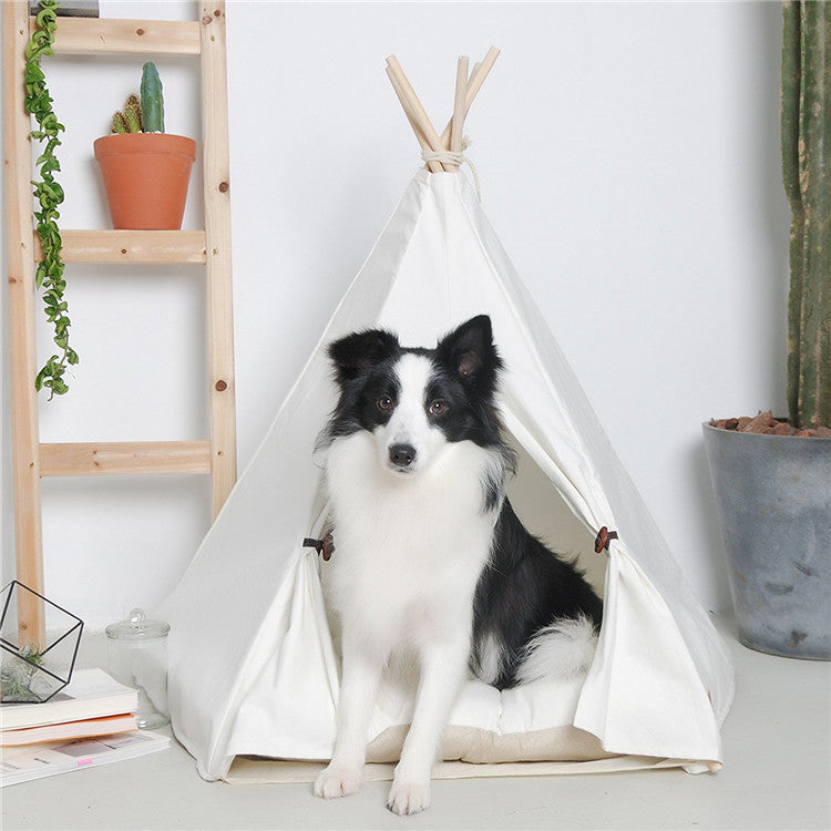 Black and white dog sitting inside a white pet teepee with cushion