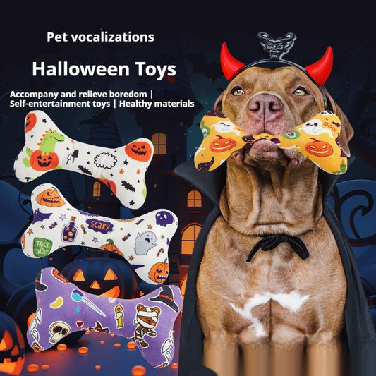 Dog holding a Halloween-themed bone toy with pumpkins and ghosts while wearing a devil costume