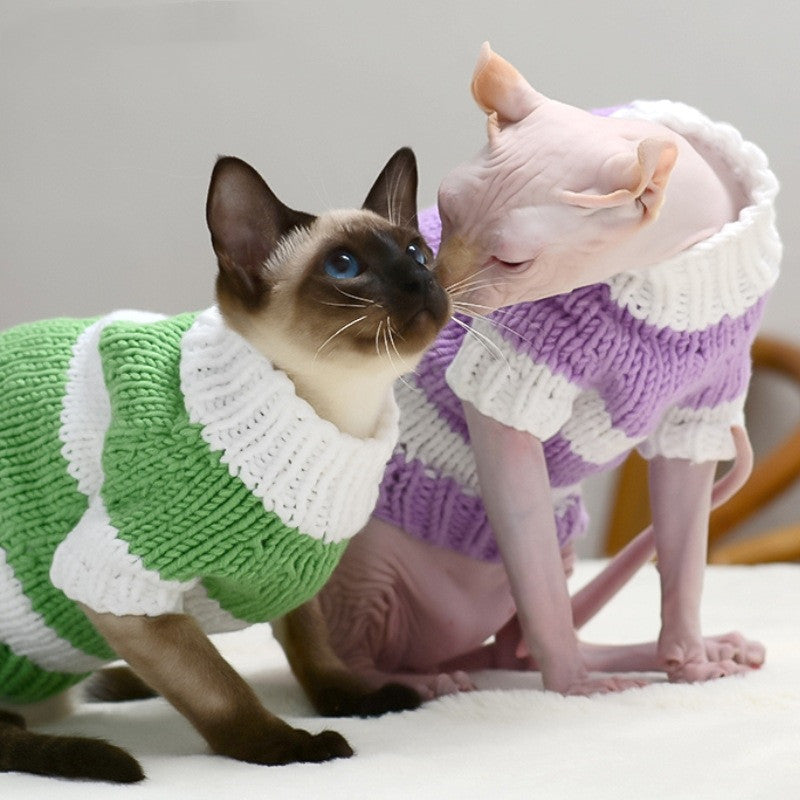 Two cats in green and lavender wool sweaters nuzzling each other