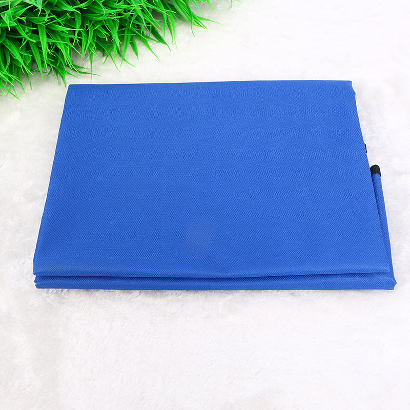 Folded blue waterproof pet seat cover on white surface with greenery background