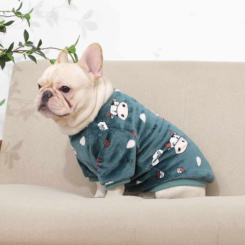 French bulldog sitting on beige couch in dark green plush pajamas with cute cow prints