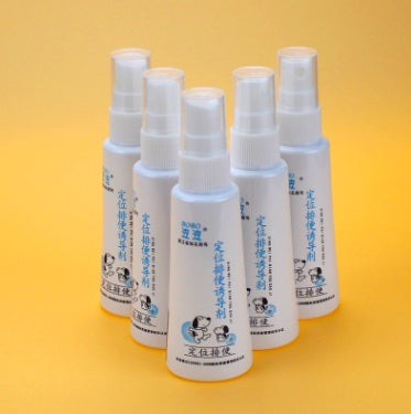 Multiple white spray bottles of pet defecation inducer with blue and black pet-themed labels arranged on yellow background