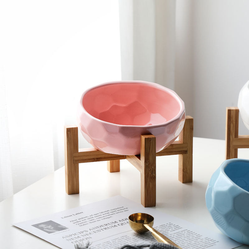 Pink ceramic pet bowl on bamboo stand in bright natural light