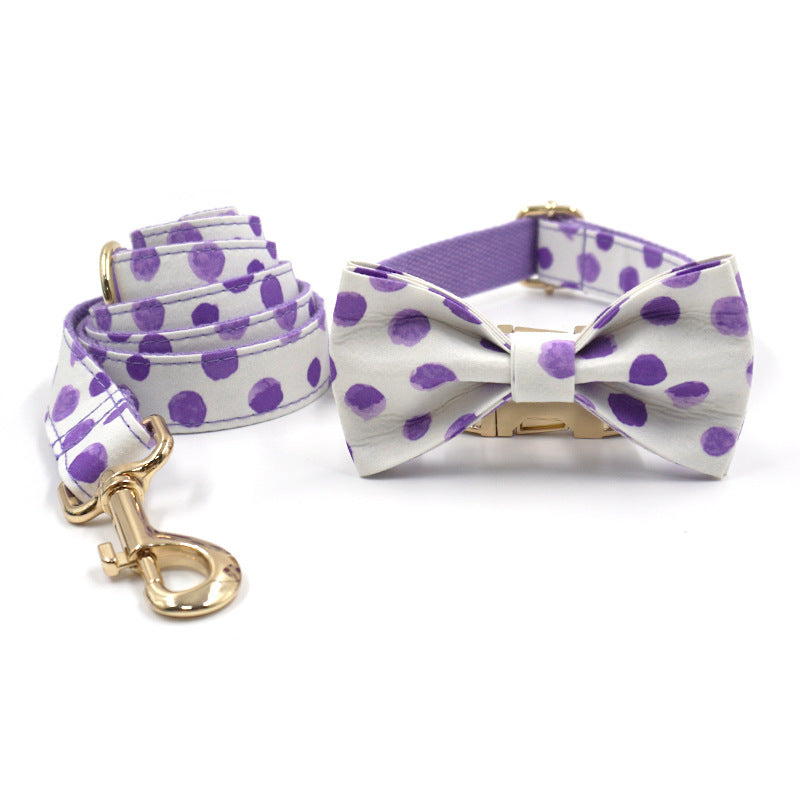 Dog collar and leash set with purple polka dots and attached bow tie, laid flat