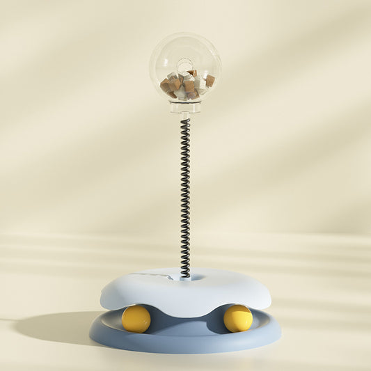 Blue interactive cat treat toy with clear treat container and spring stem on soft beige background