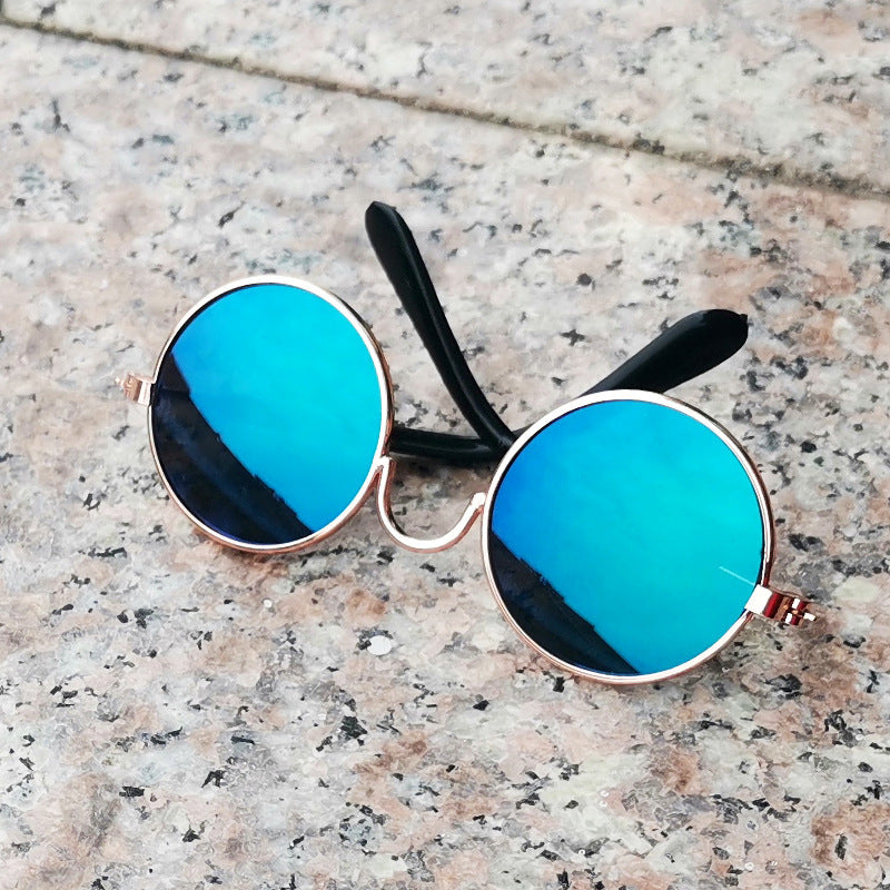 Metallic gold-framed round sunglasses with blue mirrored lenses on stone surface