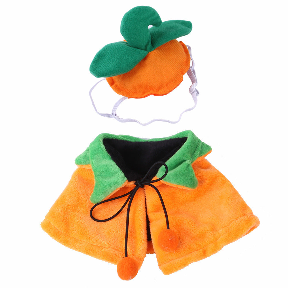 Close-up of pumpkin hat with green leaves and reversible pumpkin cloak with green collar and string tie with orange pom-poms arranged on white background.