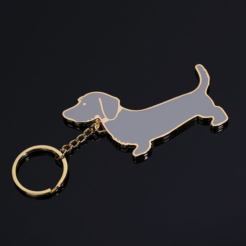 Metal dachshund dog keychain with grey enamel and gold-tone edges on black background