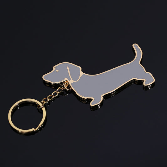 Metal dachshund dog keychain with grey enamel and gold-tone edges on black background