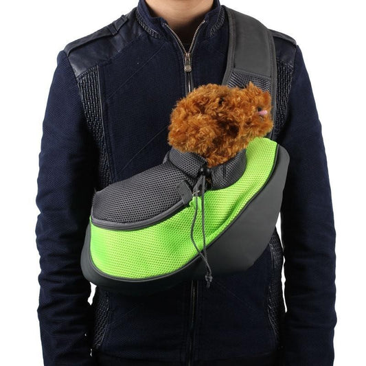 Person wearing green and gray pet sling carrier with small brown dog inside