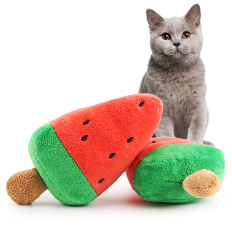 Plush toy shaped like a watermelon popsicle with red and green colors beside a gray cat