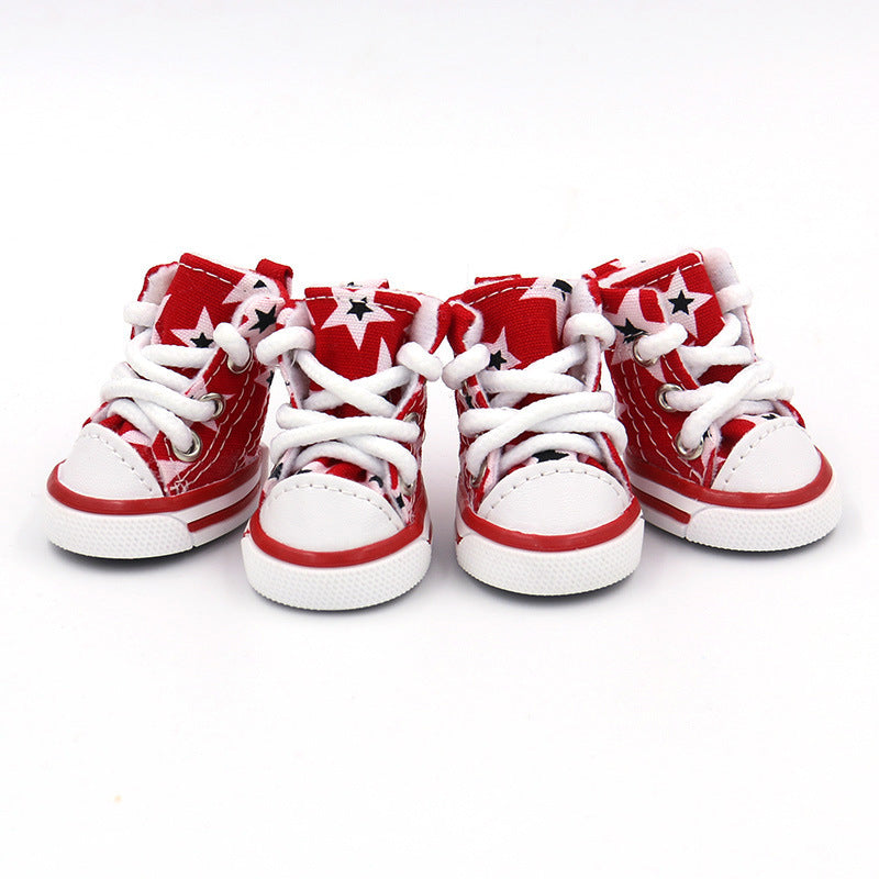 Four black and white star print dog shoes side by side showing front view with white laces