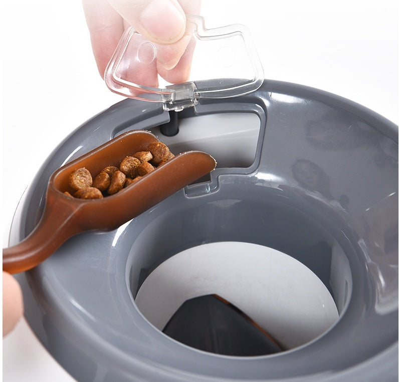 Close-up of hand placing treats into feeder's top compartment with a plastic scoop