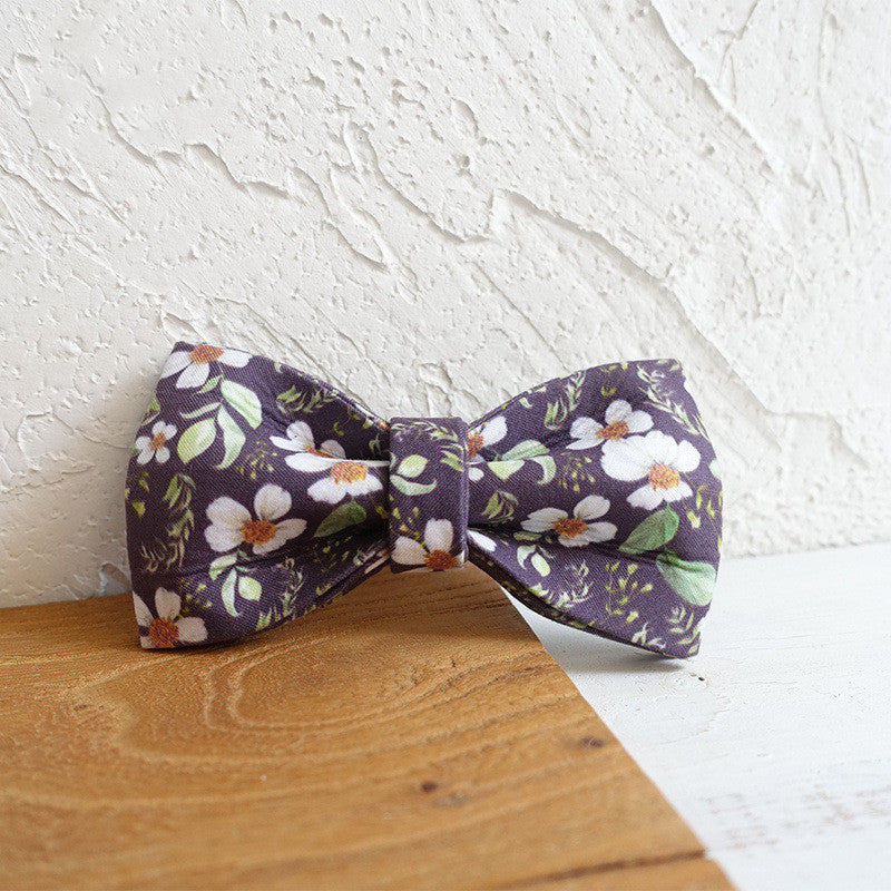 Detachable floral bow tie accessory set on wooden surface with textured white background