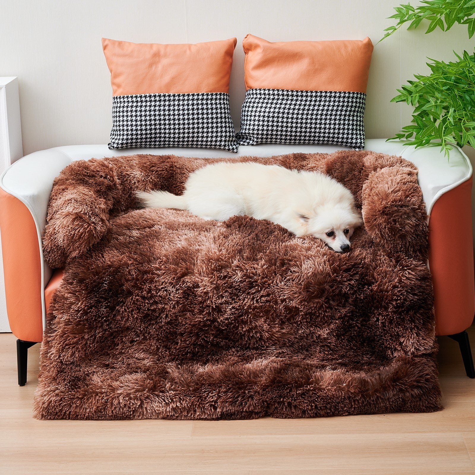 White dog comfortably resting on brown plush pet mat nest placed on living room floor near orange couch