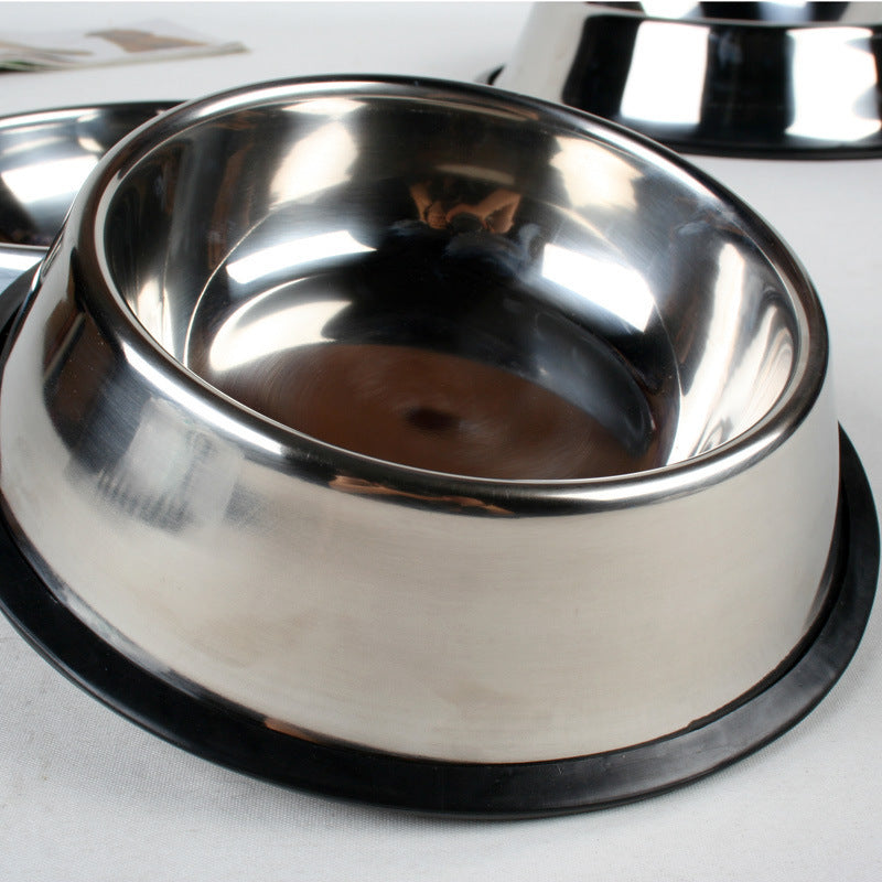 Close-up view of stainless steel pet bowl with black non-slip rubber base on white fabric background