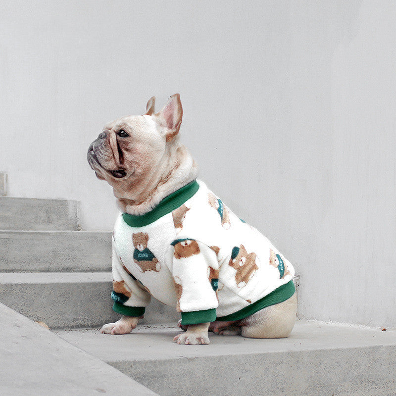 French Bulldog wearing white fleece dog sweater with teddy bear pattern and green ribbed edges sitting on concrete stairs