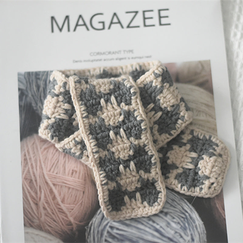 Close-up of gray-beige plaid knitted scarf on a magazine cover featuring yarn balls