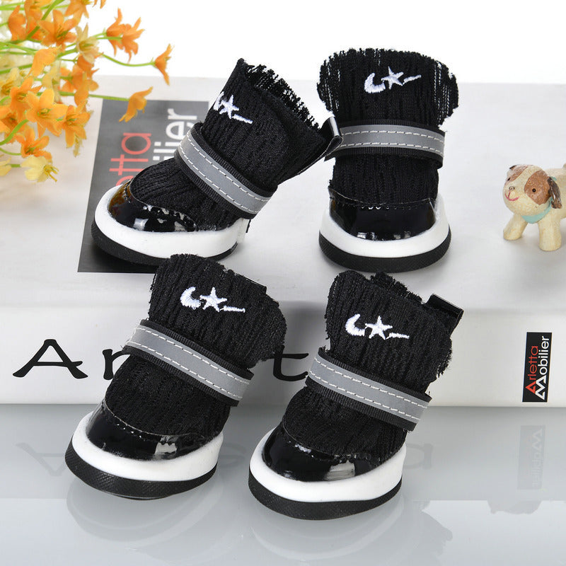Black knit dog booties with white sole and reflective strap displayed on white surface