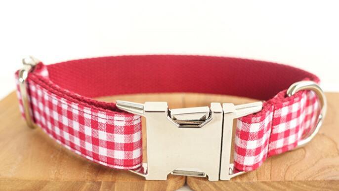 Front view of red checkered dog collar with metal buckle and D-ring on wooden base