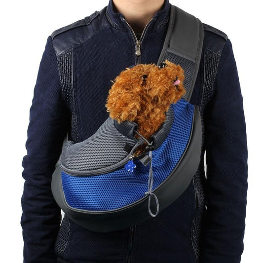 Person wearing blue and gray pet sling carrier with small brown dog inside
