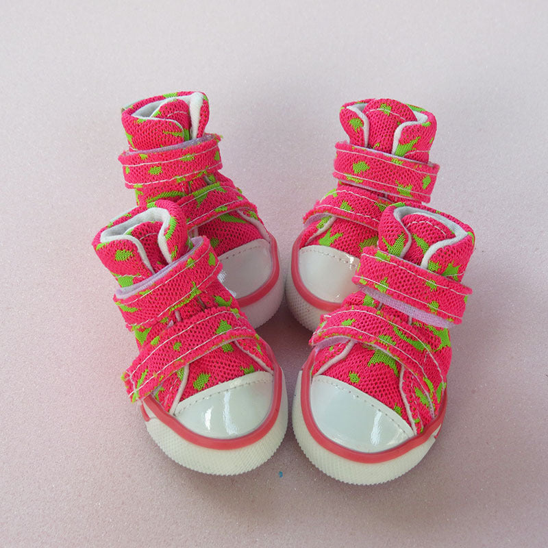 Two pink star-patterned high-top dog sneakers shown front side by side on pale surface.