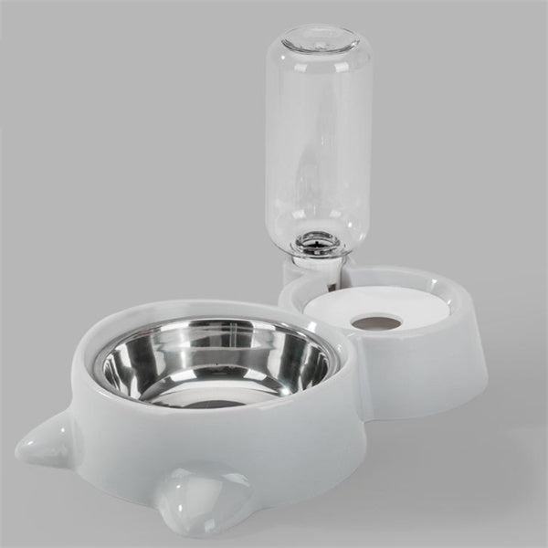 White automatic pet feeding station with stainless steel bowl and water bottle on plain background