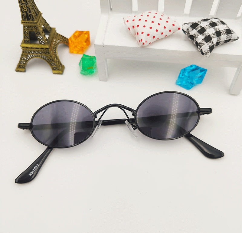 Black oval dog sunglasses toy on white background with small colorful decorative miniatures
