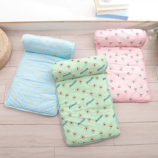 Three folded cooling pet mats with pillow bolsters in pastel colors and cute fruit prints: blue banana, green avocado, and pink peach on wooden floor