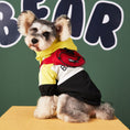 Load image into Gallery viewer, Small dog in yellow, black, and white jacket with hood and attached small red backpack sitting on a yellow platform
