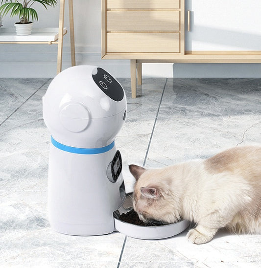 White and blue automatic pet feeder dispensing dry food to a cat on tiled floor