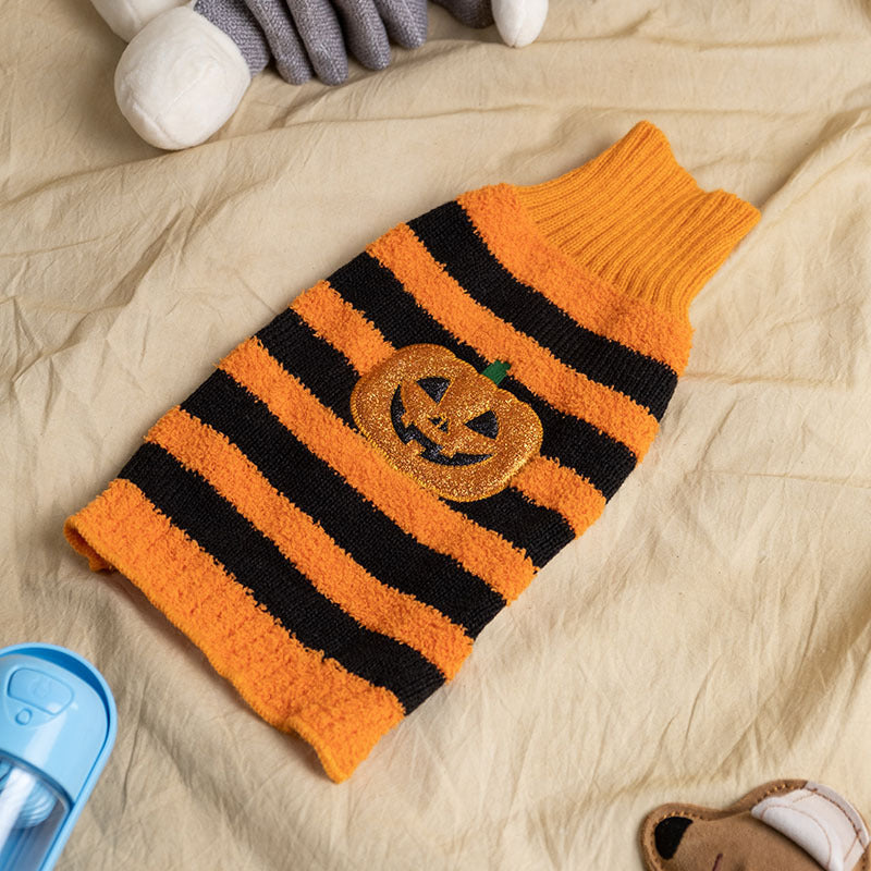 Orange and black striped Halloween pumpkin dog sweater folded on beige fabric