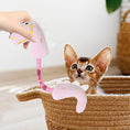 Load image into Gallery viewer, Small striped kitten watching a person hold up a pink plush dinosaur cat toy inside a wicker basket
