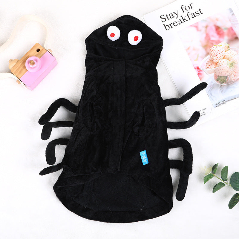 Black plush spider pet hoodie laid flat on white surface next to a pink toy camera and a floral magazine