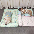 Cargar la imagen en la vista de la galería, Two small dogs lying comfortably on pastel-colored cooling pet mats with attached pillows, one with avocado print and the other with a peach design
