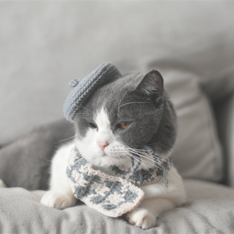 Gray-beige plaid knitted scarf laid on a magazine with yarn balls in the background