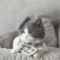 Load image into Gallery viewer, Gray-beige plaid knitted scarf laid on a magazine with yarn balls in the background
