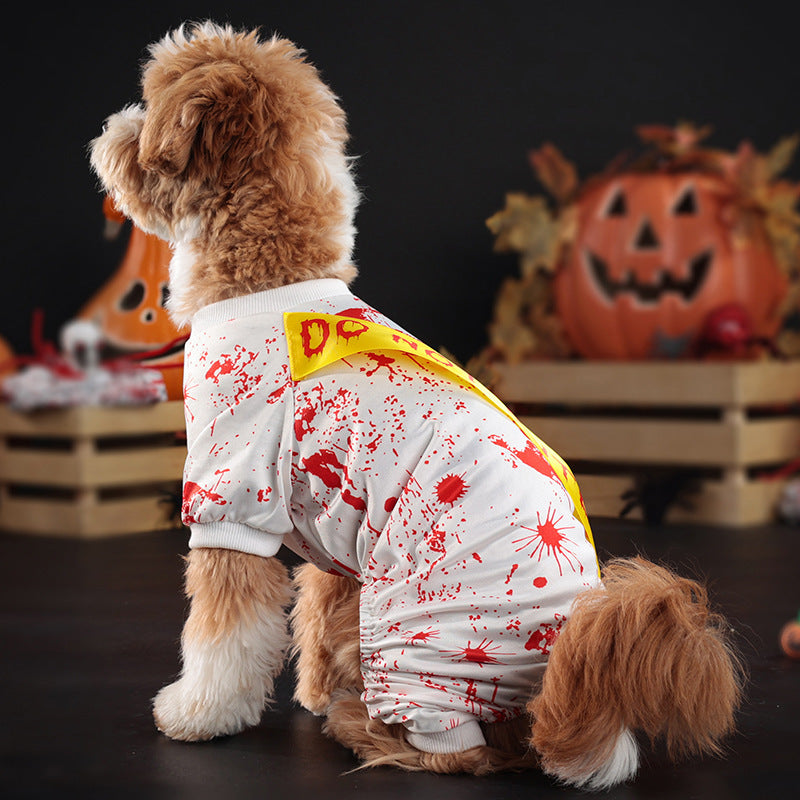 Side view of dog in white costume with red blood splatter pattern and yellow Do Not Enter sash, Halloween decor in background