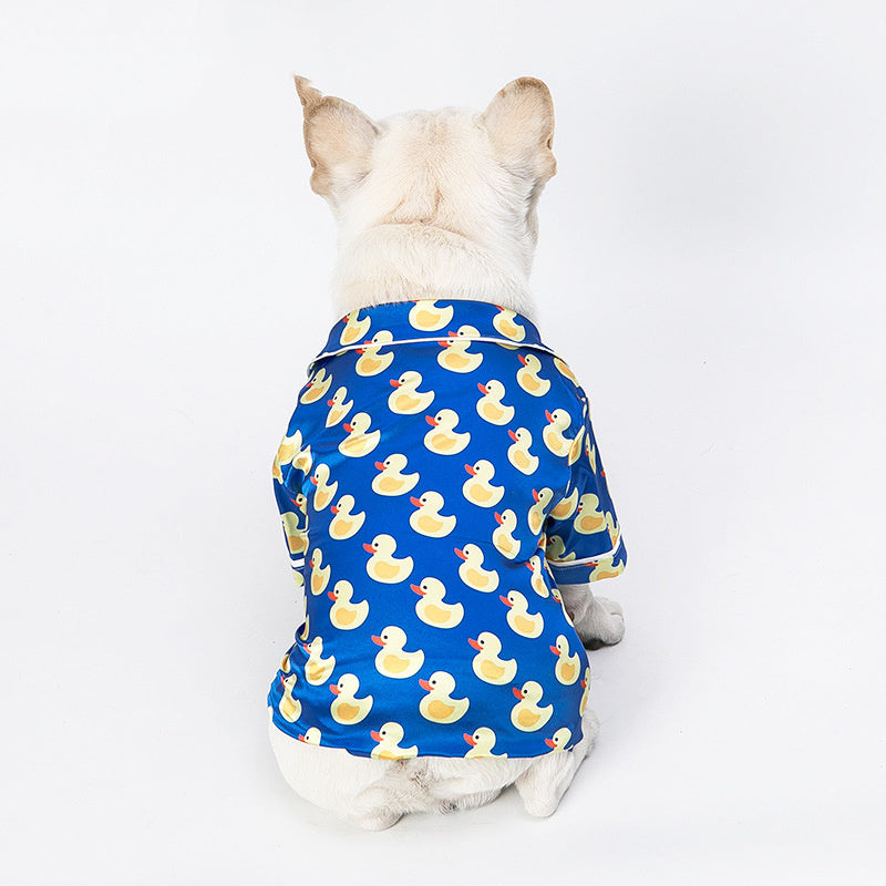 Back view of a white dog wearing the blue duck print shirt, seated facing away