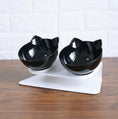 Load image into Gallery viewer, Black pair of cat ear bowls on elevated white stand photographed on wood
