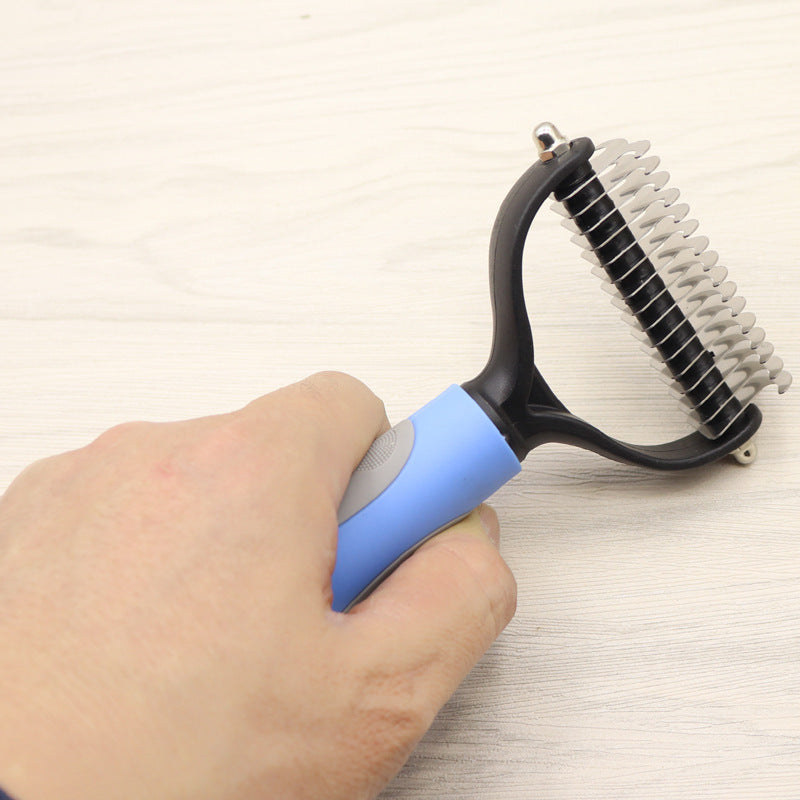 Blue and grey handled dog comb held in hand showing stainless steel blades