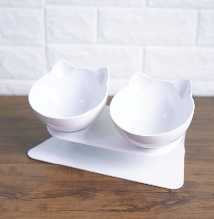 White pair of cat ear bowls on an elevated stand on a wooden surface