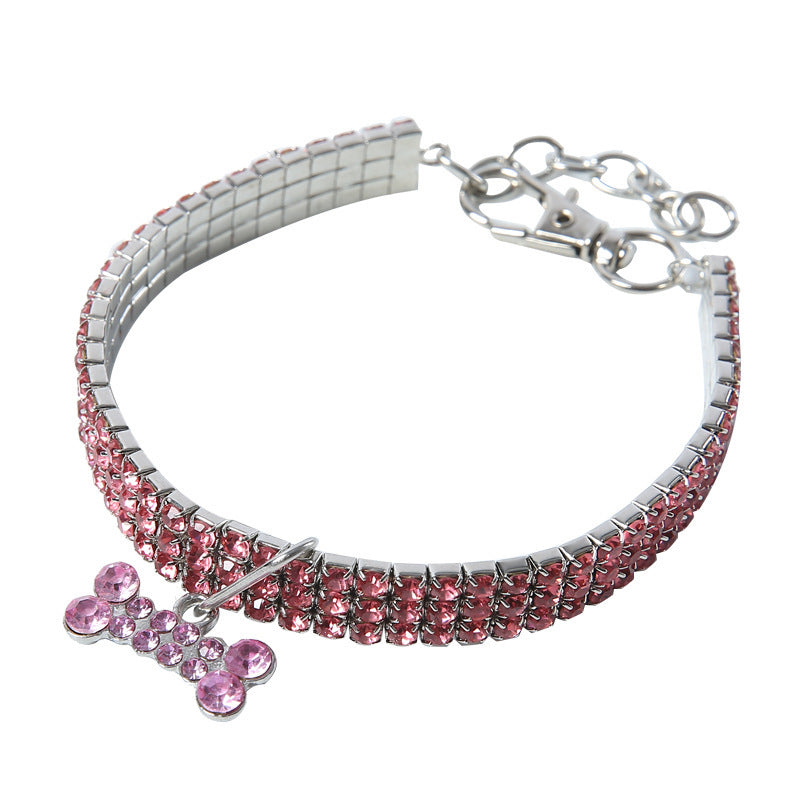 Pink rhinestone dog collar laid flat with crystal bone charm and metal clasp